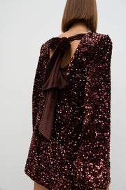 Sequined dress with a bow detail on a plain background