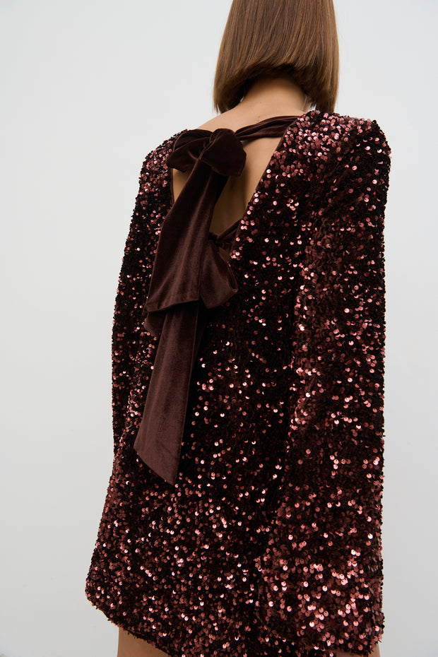 Sequined dress with a bow detail on a plain background
