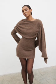 Woman wearing a brown knitted dress against a white background
