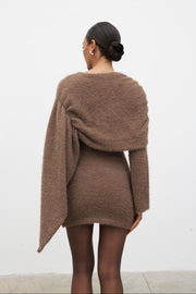 Woman wearing a brown sweater dress against a white background