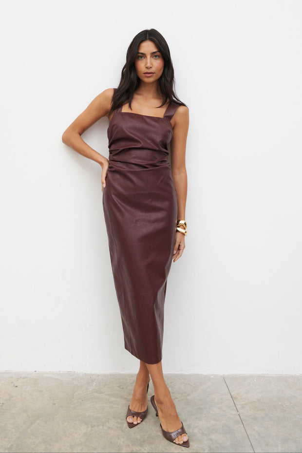 Woman wearing a brown leather dress against a white wall