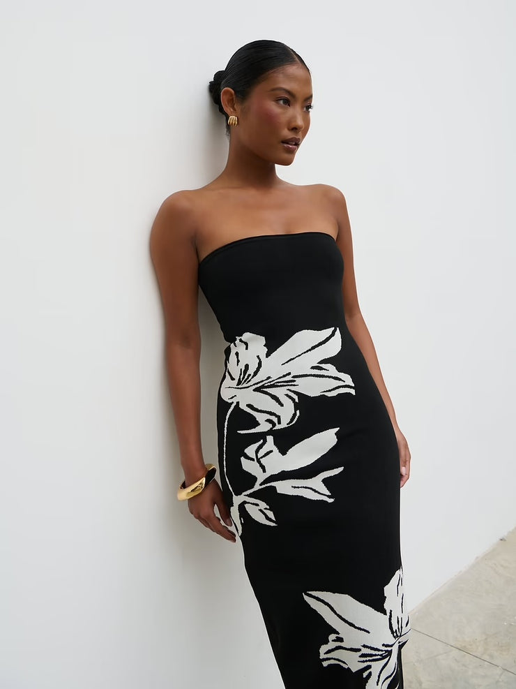 Woman wearing a black strapless dress with white floral patterns against a white background