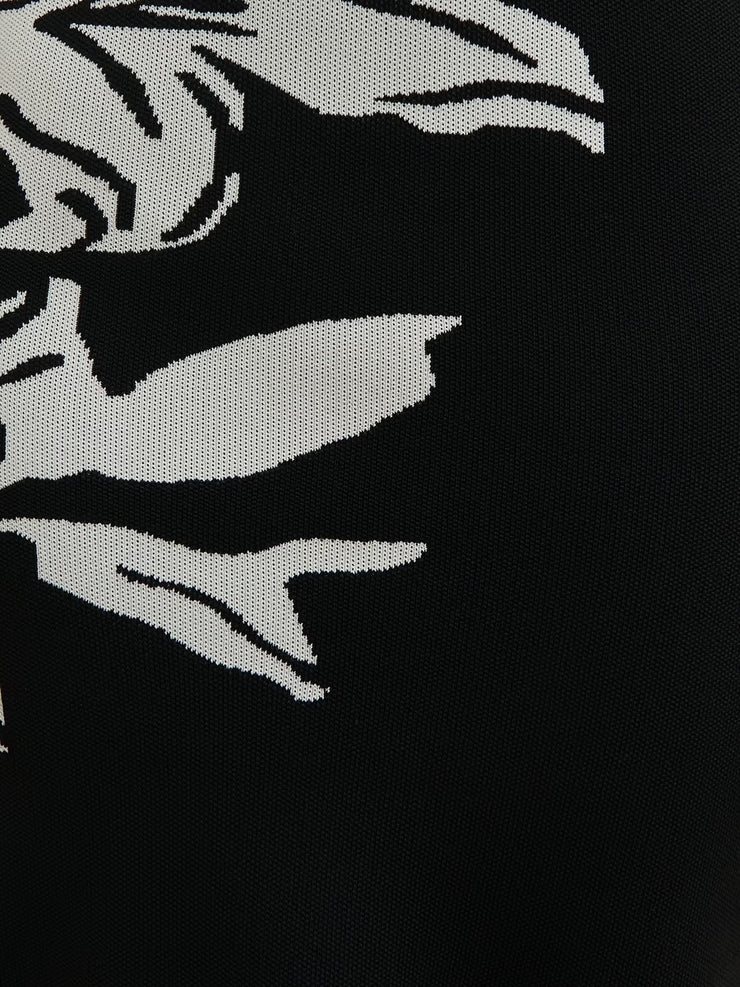 Black fabric with white embroidered design of a stylized face and hands.