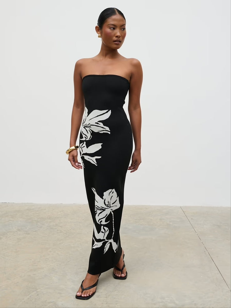 Woman wearing a black strapless dress with white floral patterns on a light gray background