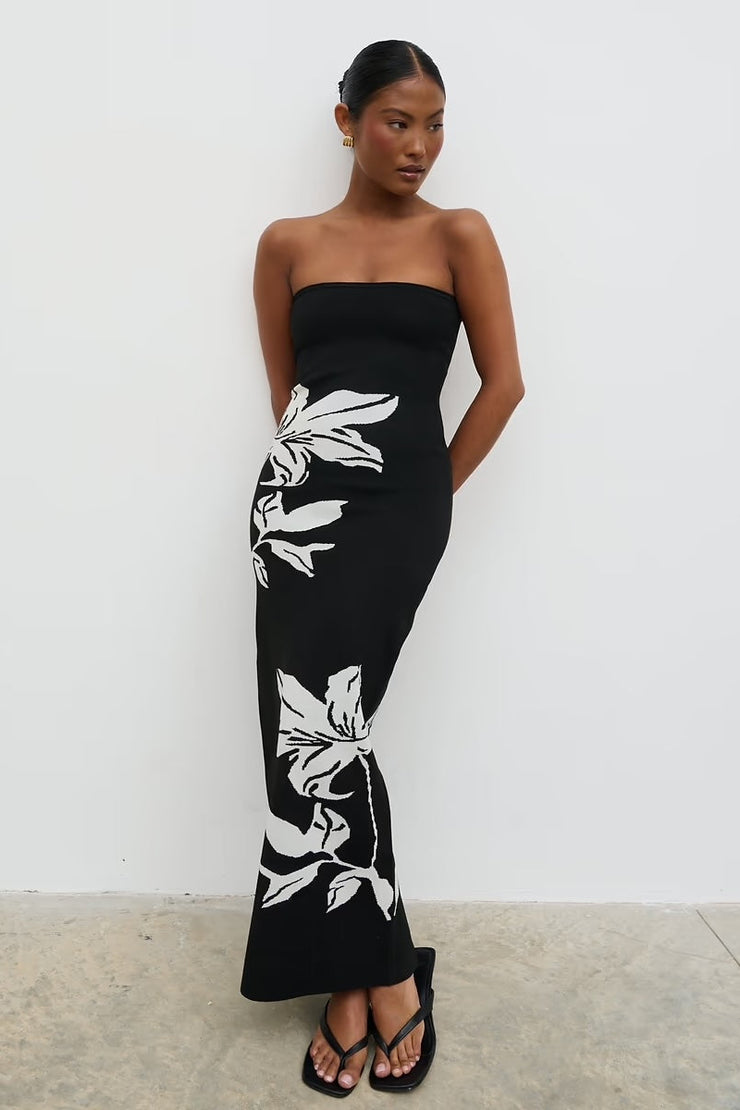 Woman wearing a black strapless dress with white floral patterns against a white background