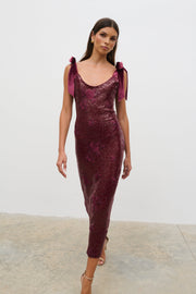 Woman wearing a burgundy sequin dress with purple accents against a white background