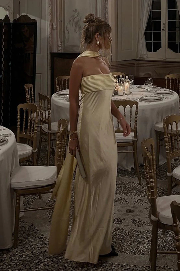 Woman in a white dress standing in a formal dining room with tables and chairs.