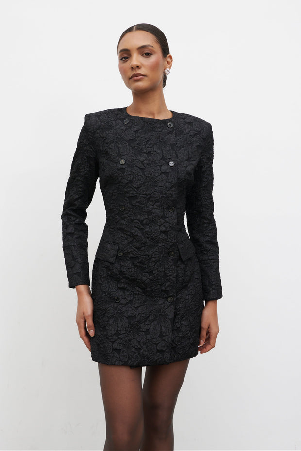 Woman wearing a black patterned dress against a white background