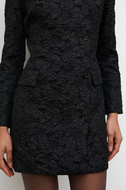 Black textured coat worn by a person on a white background