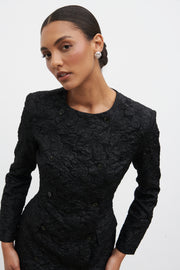 Woman wearing a black textured dress against a white background