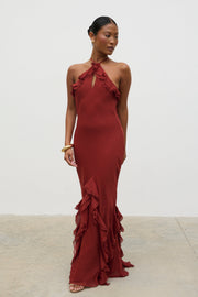 Woman wearing a burgundy evening gown with ruffled details against a white background